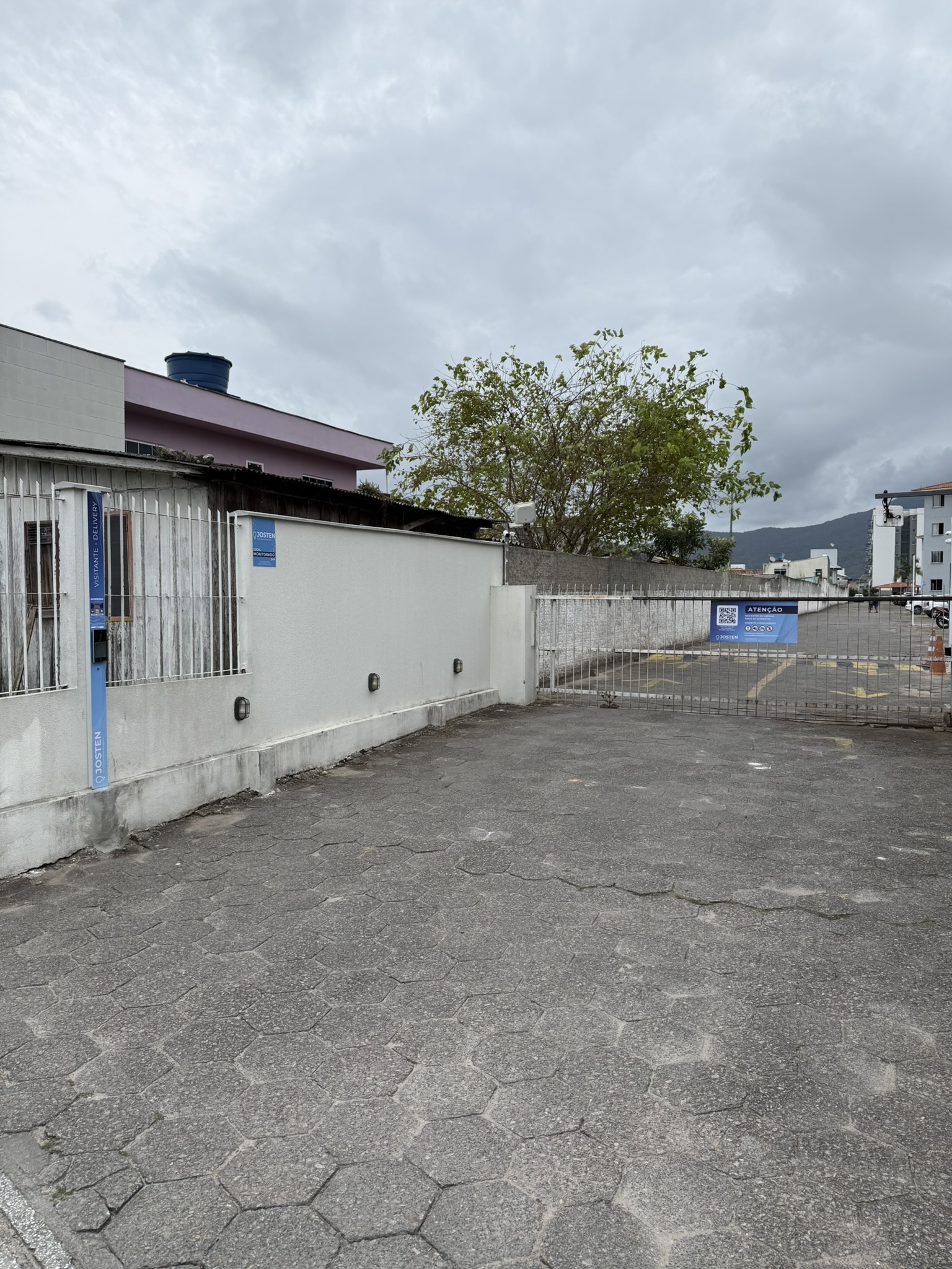 Vista da entrada do condomínio com portão e equipamento Josten junto ao muro
